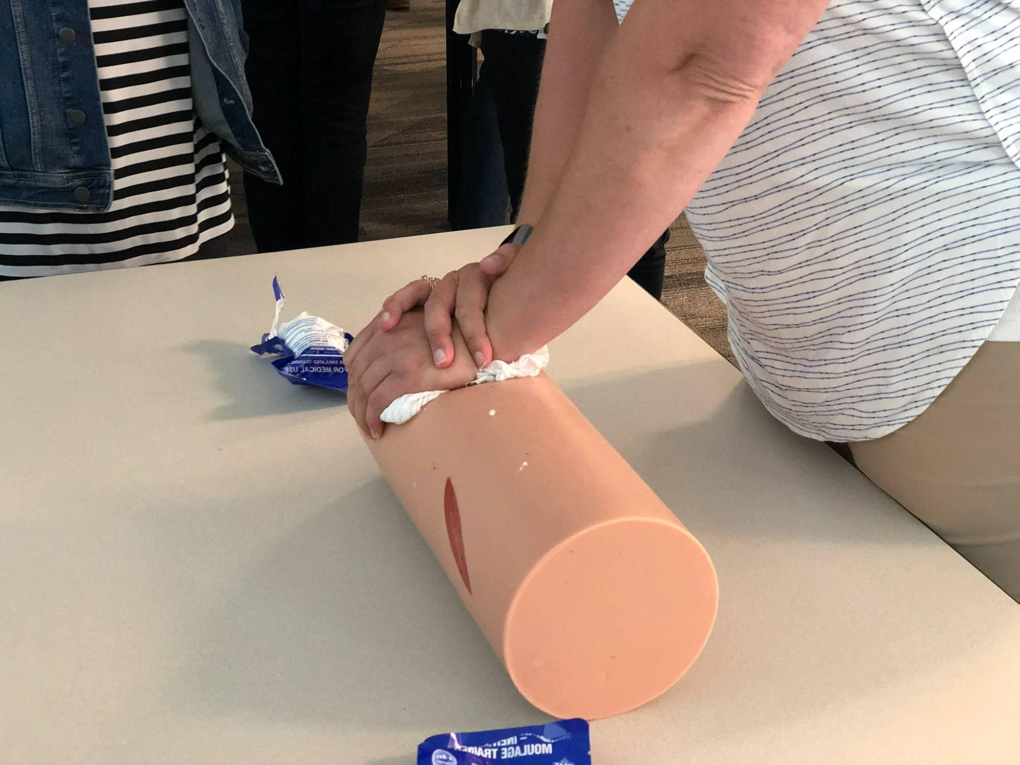 White woman's arms and hands crossed over a cylindrical item meant to simulate a person's leg, 用纱布包扎伤口